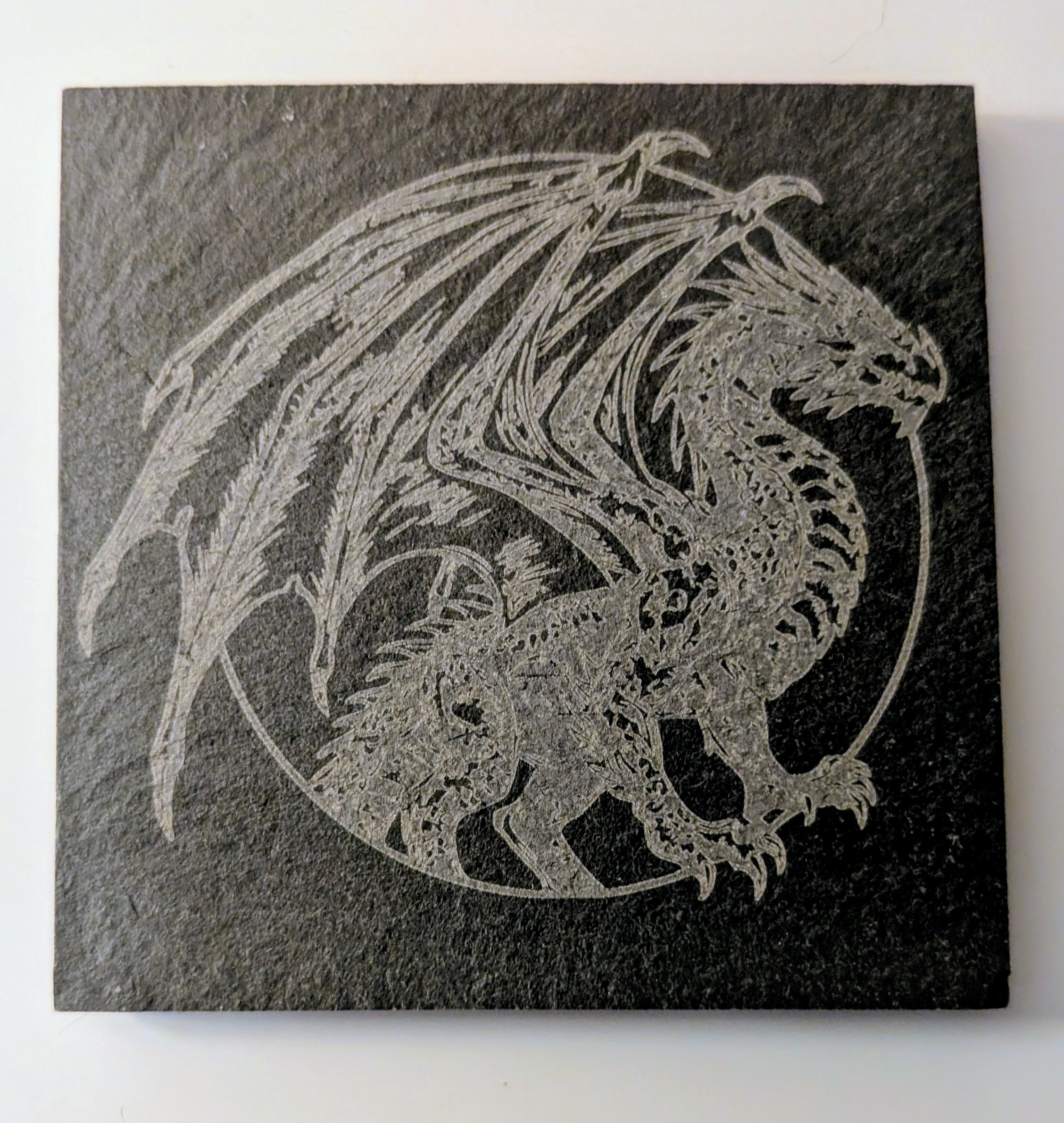 slate coaster with a dragon engraved on it
